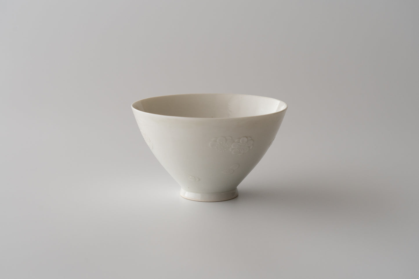 Kakiemon white porcelain bowl with embossed plum blossom design